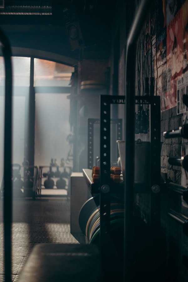 Gewichtsscheiben und Trainingsrack im gedämpften Licht des Studios