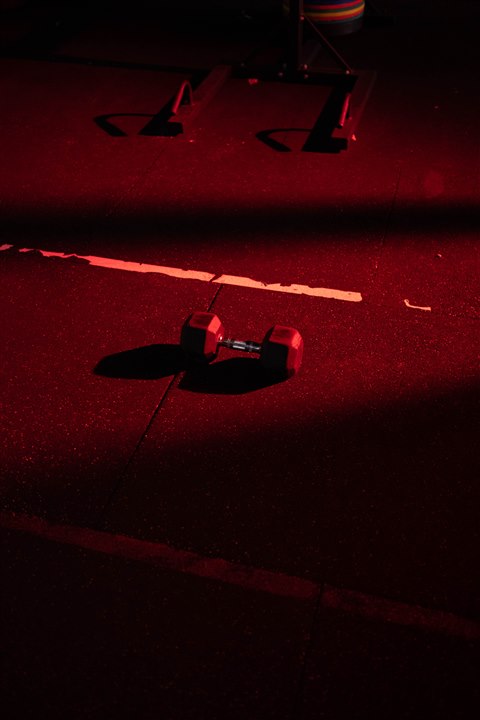 Kurzhantel auf dunklem Studioboden im roten Licht